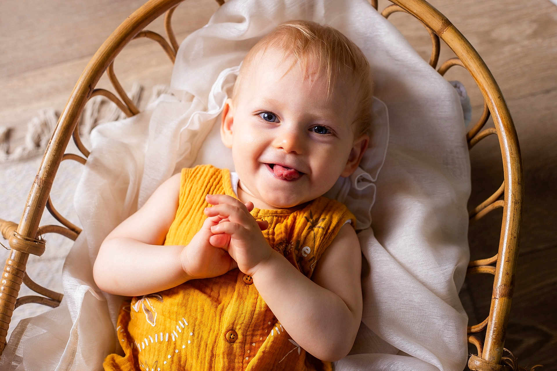 Elio a rejoint le concours — aidez-le/la à gagner de superbes lots ! baby, child, smiling, tongue_out, wicker_basket, yellow_clothing, white_fabric, indoor, cute, portrait, infant, happy, baby_clothes, wood_floor, hands, face, person, closeup, light, playful