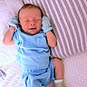 newborn, baby, sleeping, blue_clothes, mittens, pillow, bed, blanket, cozy, infant, cute, peaceful, resting, soft, striped_pillow, small_hands, small_feet, indoors, portrait, child
