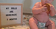 Dean is registered to the contest to win money with this photo: baby, infant, diaper, food, bread, sign, blanket, floor, wood_floor, winnie_the_pooh, roll, cute, chubby, sitting, indoor, child, homemade, humor, portrait, snack