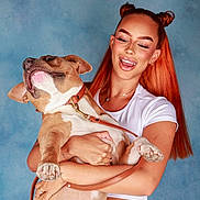 Yankee participe au concours pour gagner de l'argent avec cette photo : woman, dog, pet, happy, smiling, red_hair, space_buns, white_clothing, leash, portrait, studio, blue_background, holding, playful, animal, cute, friendly, human, joyful, casual