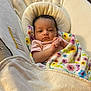 baby, infant, blanket, floral_pattern, baby_chair, clothing, face, skin, head, eyes, hands, indoor, cozy, comfort, newborn, portrait, resting, cute, young_child, soft