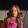 Diana is registered to the contest to win money with this photo: child, girl, long_hair, pink_shirt, heart_design, indoor, portrait, pouty_face, warm_light, sunlight, blurred_background, television, photograph, casual_clothing, person, young, cute, expression, hair, room