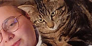Uno participe au concours pour gagner de l'argent avec cette photo : person, glasses, cat, tabby_cat, indoor, bed, white_clothing, relaxed, pet, animal, cute, comfort, lying_down, face, feline, cozy, casual, resting, home, human
