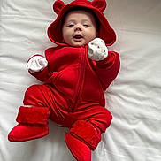 Aleksandra joined the competition — help win amazing prizes! baby, boots, child, cozy, cute, expression, face, hood, indoor, infant, lying_down, mittens, playful, portrait, red_clothing, smiling, soft_texture, warm_clothes, white_background, young