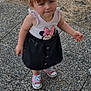 black_skirt, casual_stance, child, clothing, curious_expression, daylight, dry_grass, footwear, girl, inflatable_pool, minnie_mouse, outdoor, pebbled_path, pigtails, pink_sneakers, playful, portrait, shirt, standing, toddler