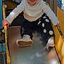 black_pants, casual, child, daisies, daytime, fun, happy, metal_slide, outdoor, person, pigtails, play, playground, slide, smiling, sneakers, sunlight, toddler, white_shirt, yellow_slide