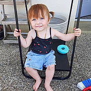 Meloane participe au concours pour gagner de l'argent avec cette photo : barefoot, black_swing, blue_eyes, broom, casual_clothing, child, denim_shorts, holding, outdoor, patio, pebble_stone, person, pigtails, playful, smiling, summer, swing, tank_top, toddler, toy