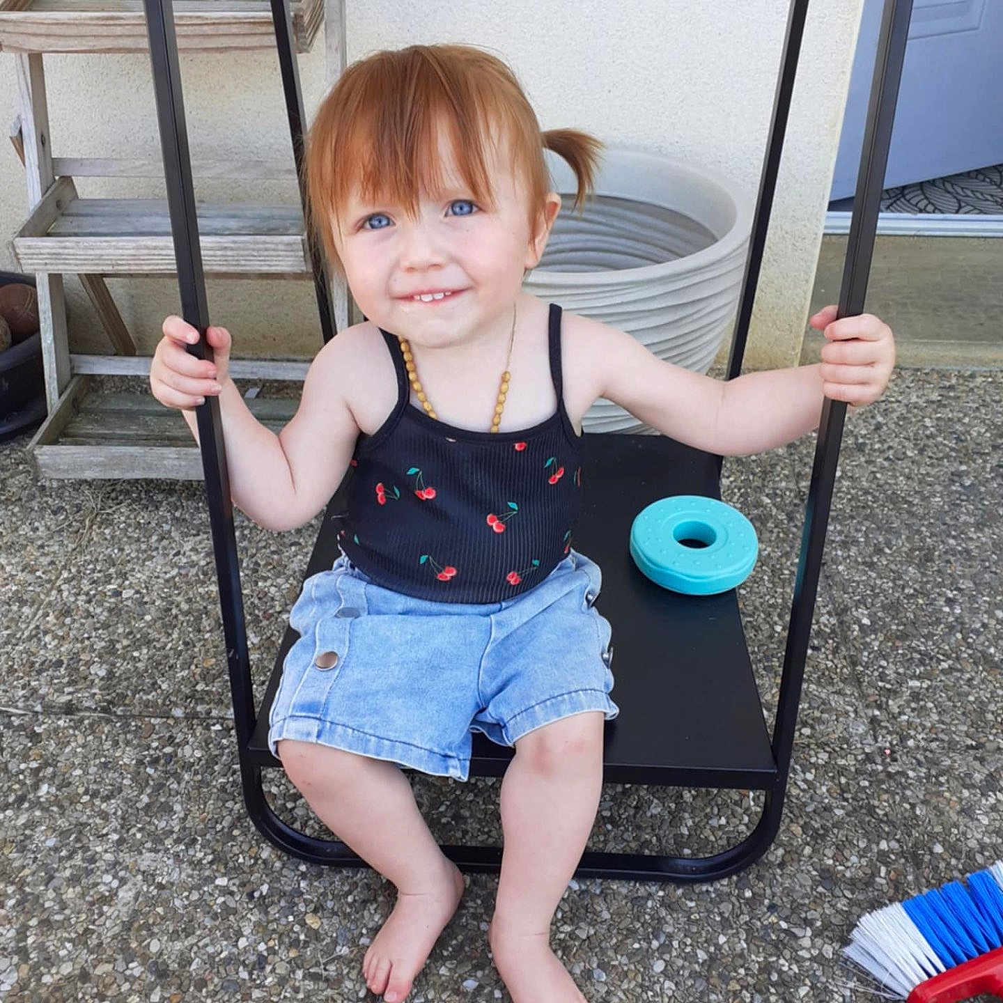 Meloane participe au concours pour gagner de l'argent avec cette photo : barefoot, black_swing, blue_eyes, broom, casual_clothing, child, denim_shorts, holding, outdoor, patio, pebble_stone, person, pigtails, playful, smiling, summer, swing, tank_top, toddler, toy