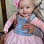 baby, child, pink_bow, dress, smile, indoor, person, hand, clothing, cute, face, denim, overalls, sparkle, tutu, headband, happy, young_child, holding, friendly