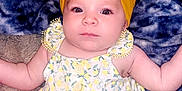 Bristol joined the competition — help win amazing prizes! baby, infant, yellow_bow, headband, blanket, blue_blanket, floral_dress, patterned_clothing, cute, lying_down, skin, arms, legs, eyes, face, buttoned_dress, indoors, soft_texture, child, portrait