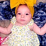 baby, infant, yellow_bow, headband, blanket, blue_blanket, floral_dress, patterned_clothing, cute, lying_down, skin, arms, legs, eyes, face, buttoned_dress, indoors, soft_texture, child, portrait