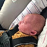baby, infant, car_seat, child, safety_harness, pacifier, striped_clothing, mustard_color, seat_belt, warning_label, no_smoking_sign, side_profile, head, face, ears, newborn, indoor, fabric, blanket, closeup