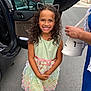 child, girl, smile, curly_hair, dress, pastel_colors, floral, headband, cat_ears, sandals, street, car, open_car_door, sidewalk, person, happy, outdoor, fashion, accessory, portrait