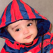 Ibrahim joined the competition — help win amazing prizes! baby, child, hoodie, striped_clothing, red, blue, couch, indoor, face, eyes, hand, cute, infant, portrait, young, expression, casual, sitting, cozy, soft_furniture