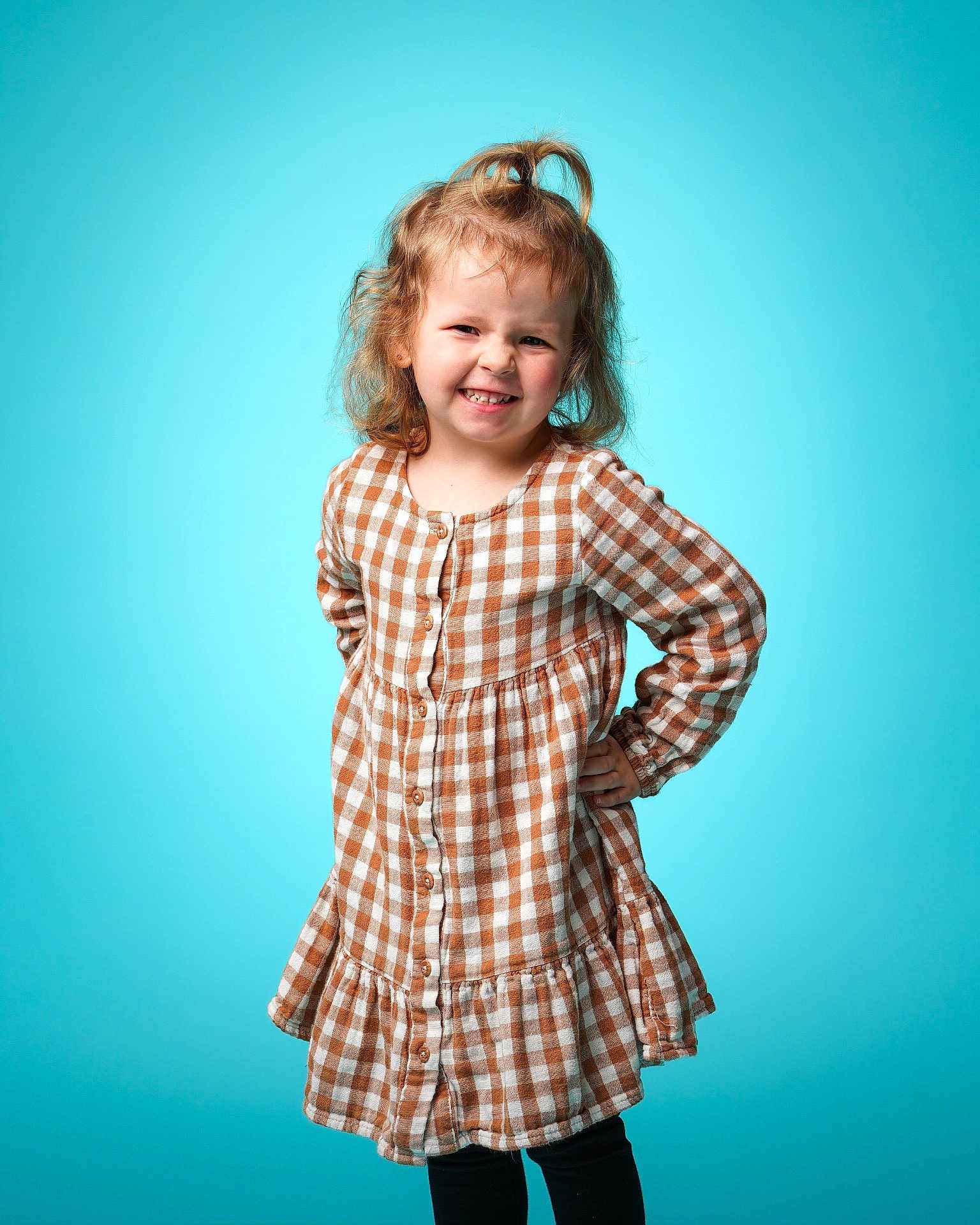 Leaghan joined the competition — help win amazing prizes! child, girl, smile, posing, dress, checkered_pattern, curly_hair, topknot, studio, blue_background, casual_clothing, happy, young, portrait, fashion, standing, playful, confident, long_sleeves, buttoned_dress