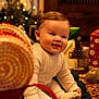 baby, carpet, child, christmas, cozy, cute, decorations, face, festive, gift, happy, holiday, holiday_lights, indoors, knitwear, present, sitting, smiling, toy, warm_lighting