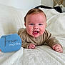 Renley is registered to the contest to win money with this photo: baby, infant, smiling, milestone_card, blanket, indoors, cute, happy, face, child, person, sweater, lying_down, celebration, skin, head, hands, cozy, young, portrait