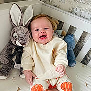 Renley joined the competition — help win amazing prizes! baby, smiling, infant, plush_toy, bunny, stuffed_animal, crib, nursery, pumpkin_pants, white_sweater, happy, child, face, cute, animal_print, wallpaper, furniture, indoor, person, sitting