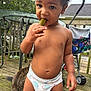 toddler, child, diaper, pickle, outdoor, deck, cat, table, stroller, clothing, wood, hand, face, curly_hair, baby, person, pet, animal, green, nature