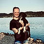 Lanna joined the competition — help win amazing prizes! woman, dog, puppy, lake, water, rocks, outdoor, nature, glasses, braids, smile, jeans, black_shirt, tattoo, sunlight, trees, hill, pet, person, casual_clothing