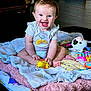 baby, child, smiling, sitting, blanket, toy, stuffed_animal, floor, indoors, happy, cute, infant, playful, clothing, person, portrait, colorful, soft, fun, joy