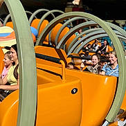 Lyana a rejoint le concours — aidez-le/la à gagner de superbes lots ! amusement_park, ride, children, family, fun, orange, smiling, people, outdoor, sunlight, metal, safety_bar, happy, group, seating, roller_coaster, daytime, excitement, casual_clothing, leisure