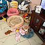 basket, blanket, blue, brown, cabinet, cozy, cushion, decor, dog, floor, furniture, indoor, pet_bed, photo_frame, pink, plush_toy, relaxing, small_dog, tile, toy