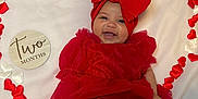 Araceli is registered to the contest to win money with this photo: baby, infant, smiling, red_dress, headband, bow, heart_shape, fabric, white_background, celebration, cute, happy, two_months, portrait, laying_down, skin, feet, hands, closeup, decorative_hearts