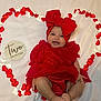 baby, infant, smiling, red_dress, headband, bow, heart_shape, fabric, white_background, celebration, cute, happy, two_months, portrait, laying_down, skin, feet, hands, closeup, decorative_hearts