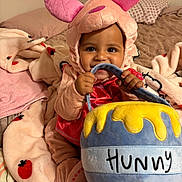 Araceli is registered to the contest to win money with this photo: baby, child, costume, plush, pink, bed, blanket, soft, cute, smiling, face, person, indoors, toy, honey_pot, chewing, ears, sleepwear, toddler, happy