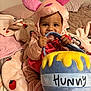 baby, child, costume, plush, pink, bed, blanket, soft, cute, smiling, face, person, indoors, toy, honey_pot, chewing, ears, sleepwear, toddler, happy