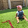 Araceli joined the competition — help win amazing prizes! baby, child, grass, outdoor, smiling, headband, denim, overalls, flower_petals, heart_shape, greenery, sunlight, happy, playing, sitting, portrait, cute, infant, lawn, garden