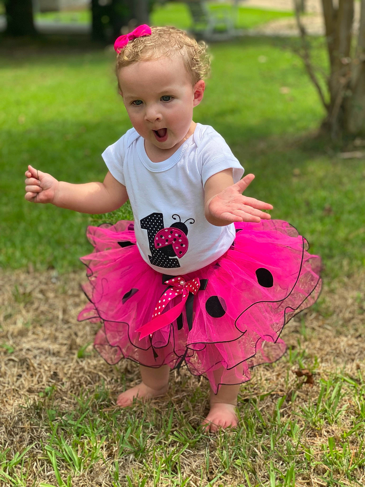 Emerie is registered to the contest to win money with this photo: baby, baby_toddler_clothing, barefoot, child, event, fun, grass, grass_family, happy, lawn, leisure, magenta, pattern, people_in_nature, person, pink, plant, recreation, surprise, t_shirt