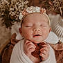 baby, infant, wrapped, blanket, headband, flower, knitted_heart, peaceful, sleeping, hands, closeup, soft_light, portrait, dried_flowers, cozy, cute, newborn, warm_colors, face, serene