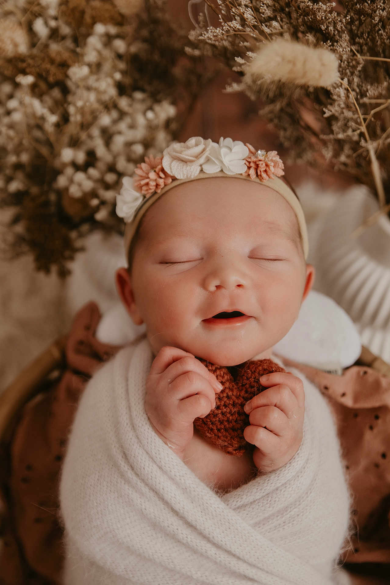 Cléa a rejoint le concours — aidez-le/la à gagner de superbes lots ! baby, infant, wrapped, blanket, headband, flower, knitted_heart, peaceful, sleeping, hands, closeup, soft_light, portrait, dried_flowers, cozy, cute, newborn, warm_colors, face, serene