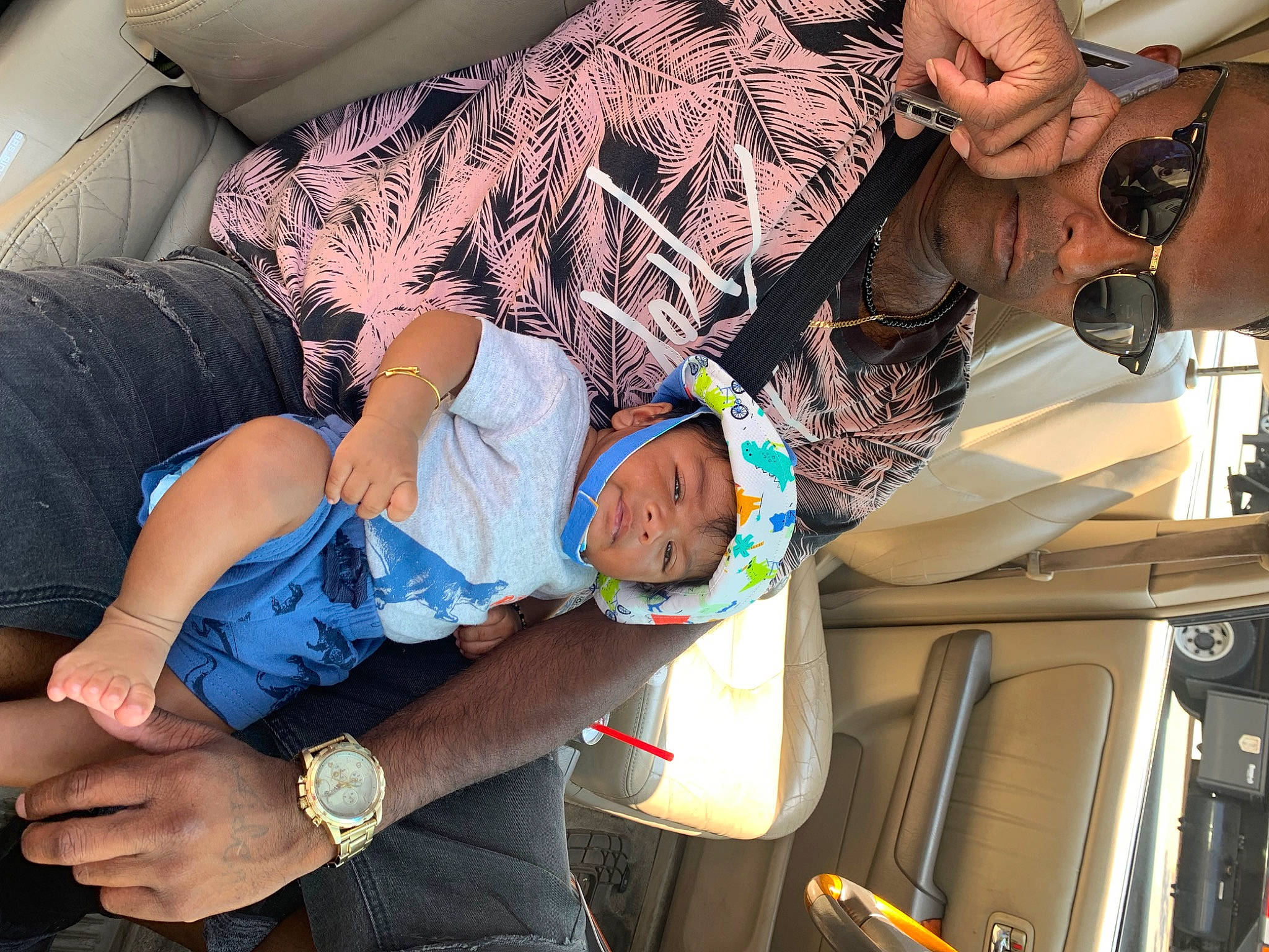 Armani is registered to the contest to win money with this photo: arm, baby, child, comfort, elbow, electric_blue, finger, fun, hand, headwear, human_leg, joint, knee, lap, leg, person, sitting, thigh, toddler, tree