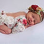 newborn, baby, sleeping, flower_headband, floral_outfit, lace, infant, cute, peaceful, portrait, soft_texture, white_background, child, resting, tiny_hands, closed_eyes, delicate, adorable, cozy, studio_photo