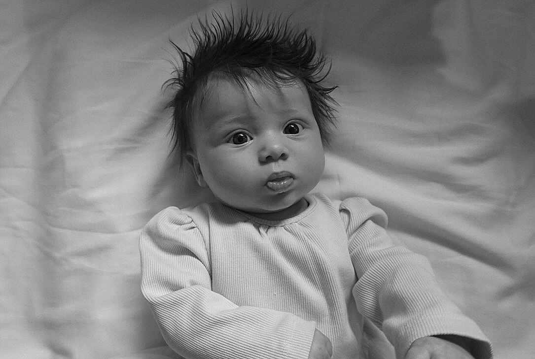 Ophelia is registered to the contest to win money with this photo: baby, infant, child, black_and_white, portrait, wide_eyes, spiky_hair, long_sleeve_shirt, ribbed_clothing, lying_down, soft_background, fabric, curious_expression, monochrome, close_up, person, cute, indoors, young, head_shot