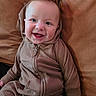 Giovanni is registered to the contest to win money with this photo: baby, child, infant, smiling, happy, portrait, sitting, cushion, couch, brown, clothing, jumpsuit, hooded, zipper, indoor, cozy, face, eyes, hands, photography