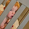 Bennett is registered to the contest to win money with this photo: baby, child, crib, red_hair, tongue_out, polka_dot, bedding, infant, bars, cute, playful, peek, face, skin, person, indoors, bed, head, young_child, expression