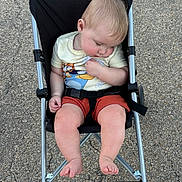Bennett joined the competition — help win amazing prizes! baby, child, toddler, sleeping, stroller, outdoor, pavement, clothing, shorts, tshirt, barefoot, metal, black_fabric, seatbelt, head, legs, feet, person, resting, peaceful