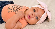 Calissia is registered to the contest to win money with this photo: baby, infant, child, lying_down, headband, pink_bow, onesie, peach_color, soft_blanket, cute, portrait, face, eyes, skin, hand, expression, indoor, clothing, adorable, young