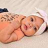 baby, infant, child, lying_down, headband, pink_bow, onesie, peach_color, soft_blanket, cute, portrait, face, eyes, skin, hand, expression, indoor, clothing, adorable, young