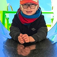 Aaron participe au concours pour gagner de l'argent avec cette photo : child, boy, glasses, cap, scarf, smiling, playground, slide, blue_sky, outdoor, reflection, happy, casual_clothing, play, fun, young, person, daylight, colorful, park