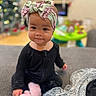 Paisley is registered to the contest to win money with this photo: baby, child, headband, black_clothing, slipper, blanket, couch, indoor, portrait, cute, infant, smile, face, person, home, soft_texture, holiday_decor, bokeh, cozy, sitting