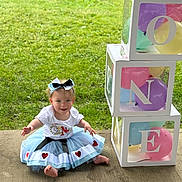 Barbara is registered to the contest to win money with this photo: toddler, child, birthday, balloons, tutu, bow, grass, outdoor, concrete, colorful, smiling, sitting, cute, celebration, party, decorations, clothing, person, happy, festive