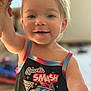 Barbara is registered to the contest to win money with this photo: toddler, child, smiling, tank_top, colorful_clothing, happy, face, arm_raised, indoors, blurry_background, person, cute, blue_eyes, short_hair, skin, playful, cartoon, monster_truck, graphic_tee, celebration