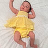 baby, infant, yellow_dress, clothing, lying_down, blanket, white_background, cute, child, newborn, skin, face, legs, arms, indoors, portrait, expression, toddler, person, sleepwear