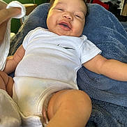 Kamari joined the competition — help win amazing prizes! baby, infant, smile, white_onesie, blanket, blue_blanket, indoor, child, happy, soft_texture, person, skin, hand, sitting, cute, room, shelf, clothing, comfort, cozy