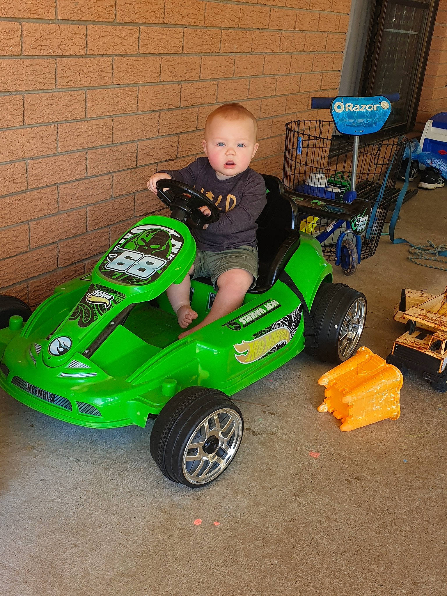 Frederick is registered to the contest to win money with this photo: car, go_kart, green, land_vehicle, person, play, riding_toy, surprise, toddler, toy, toy_vehicle, vehicle